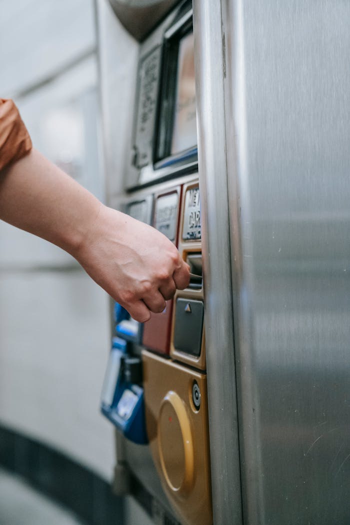 Close-up of a hand operating a subway ticket machine in a city.